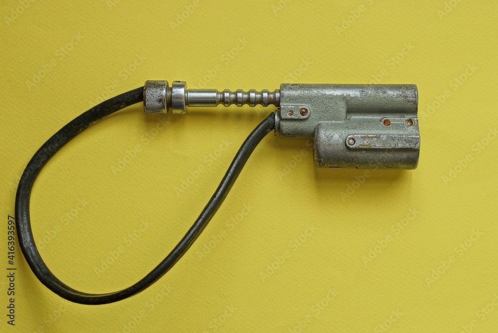 one old closed bicycle lock with a gray metal core and a black cable lies on a yellow table one old closed bicycle lock with a gray metal core and a black cable lies on a yellow table