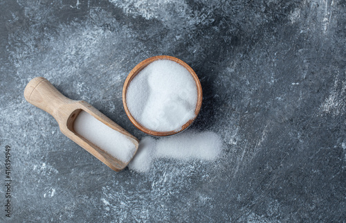 Salt in a wooden spoon on a marble background