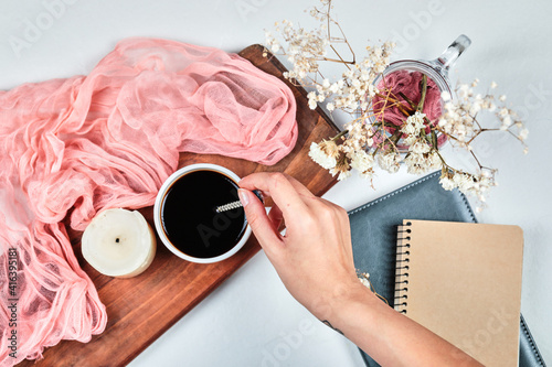 Hand holding a cup of coffee on the wooden board with candle photo