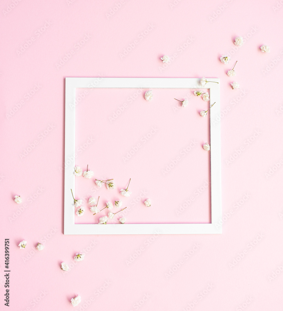 Delicate gypsophila flowers scattered on a light pink background and white frame.  Creative minimal spring concept. Wedding , Woman's day greeting card. Flat lay. 