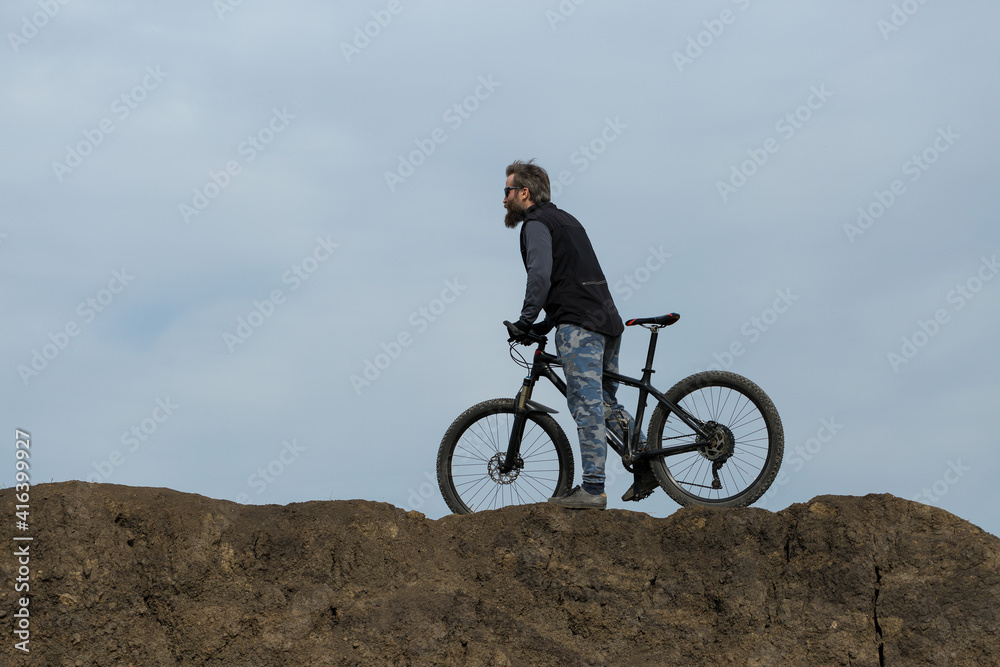 Sports brutal bearded guy on a modern mountain bike. Beautiful view from the mountain. Panoramic view for banner. Sports brutal bearded guy on a modern mountain bike. Beautiful view from the mountain. Panoramic view for banner.