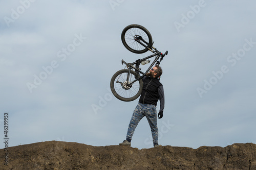Sports brutal bearded guy on a modern mountain bike. Beautiful view from the mountain. Panoramic view for banner.