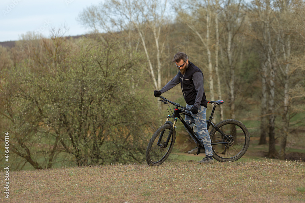 Sports brutal bearded guy on a modern mountain bike. Cyclist on the green hills in the spring. Sports brutal bearded guy on a modern mountain bike. Cyclist on the green hills in the spring.