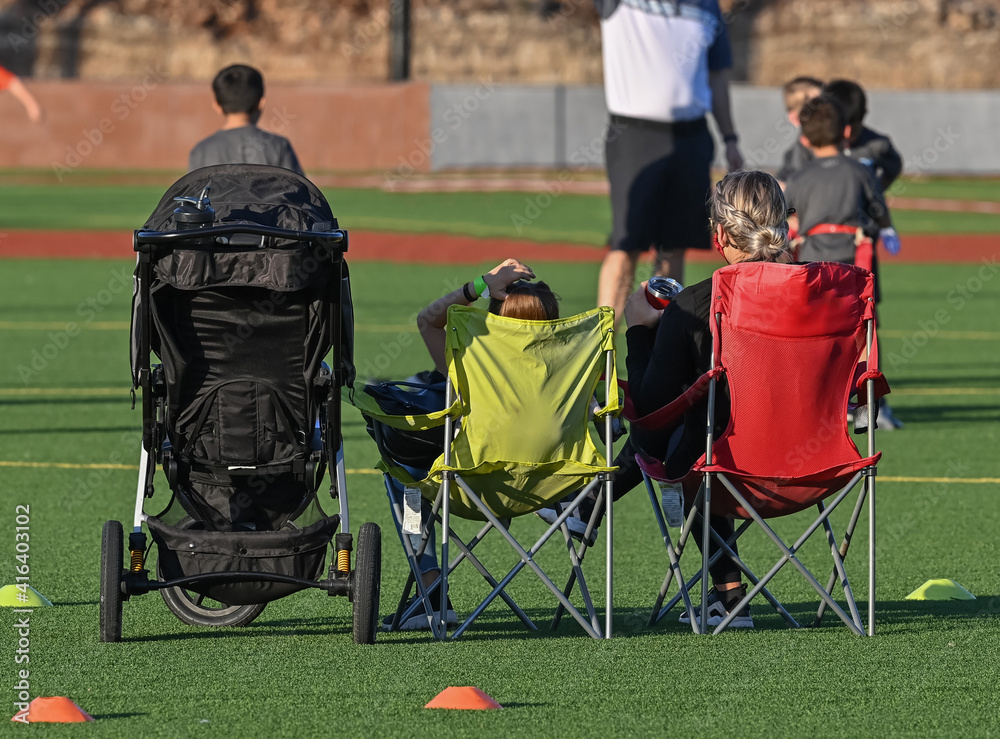 Family watching a sporting event in chairs and a stroller Family watching a sporting event in chairs and a stroller