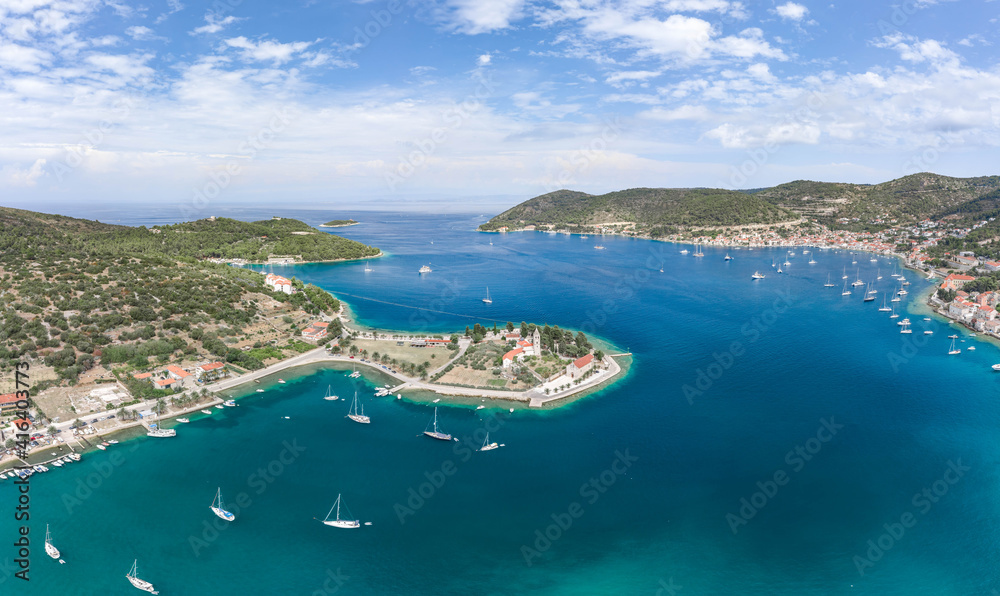 Aerial drone shot of Vis Island port with St. Jeronima church and Adriatic coastline in summer