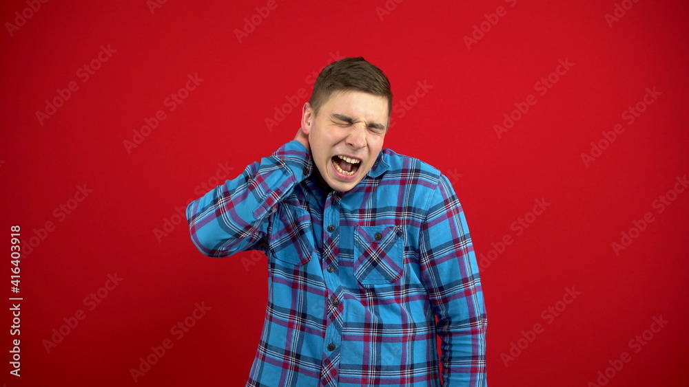 The young man has a sore nose, he touches it with his hand. Shooting on a red background. The young man has a sore nose, he touches it with his hand. Shooting on a red background.