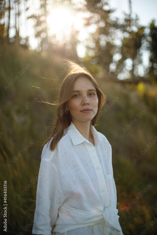 young girl in white linen clothes looks back on the blurred background of the forest. tenderness and youth young girl in white linen clothes looks back on the blurred background of the forest. tenderness and youth