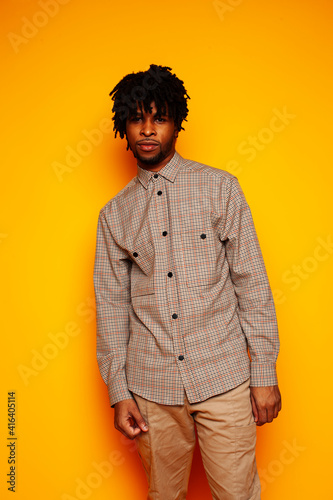 young handsome african american guy student posing cheerful and gesturing on yellow background, lifestyle people concept