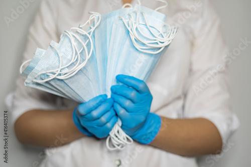 Female doctor holds many masks in her hands wearing protective blue gloves