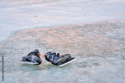 pair of men ice skates on a frozen lake with sunset reflections