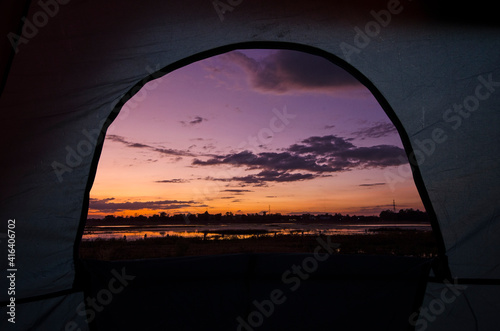 Morning light over the lake in window of camping tent