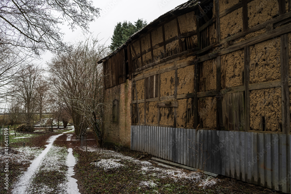 Snow-covered dirt road along the old and abandoned building.