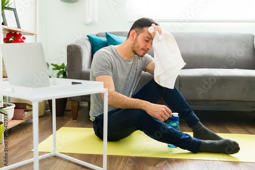 Hispanic man taking a break from working out in the living room