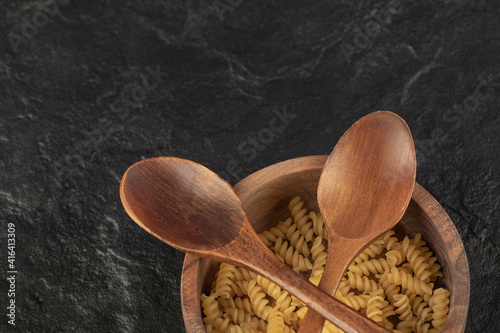 A wooden bowl full of raw girandole pasta