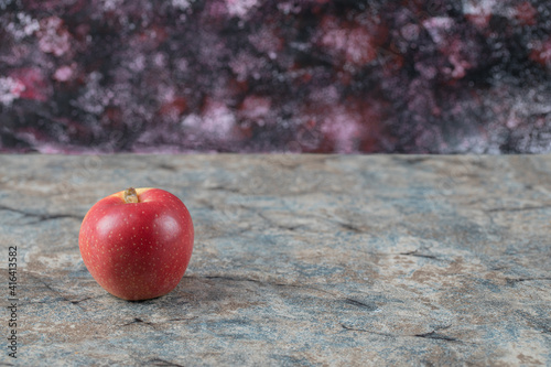 A single red apple on a marble background