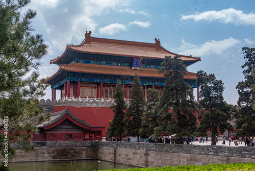 Beijing, China - April 27, 2010: Red Gate of devine Prowess building as exit of Forbidden City North side under blue cloudscape. Moat and green trees.