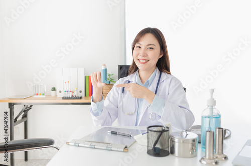 asian female doctor explaining about how to use inhaler medicine in asthma clinic  she holding and present inhaler medicine with hand