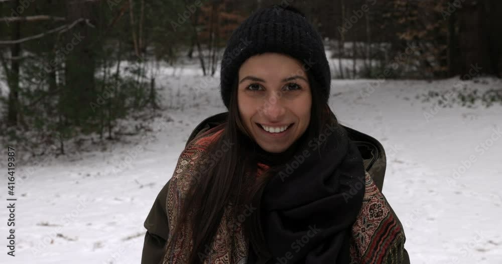 Attractive young adult woman on snowy walking path smiles towards camera - medium shot Attractive young adult woman on snowy walking path smiles towards camera - medium shot