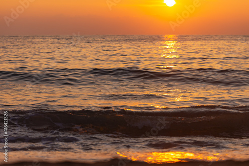 Yellow sunset from the low sun. Seashore with a sunset path on the waves.