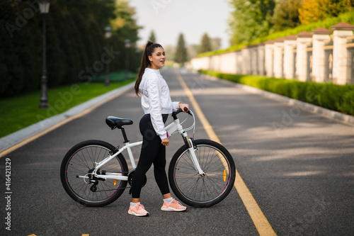 Beautiful girl posing at white bicycle. Walk in nature.