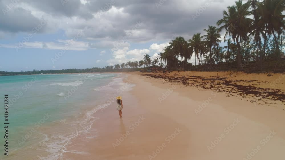 Tropical island beach and carefree woman walking on the sea sand. Freedom and relaxation. 4k aerial video Tropical island beach and carefree woman walking on the sea sand. Freedom and relaxation. 4k aerial video