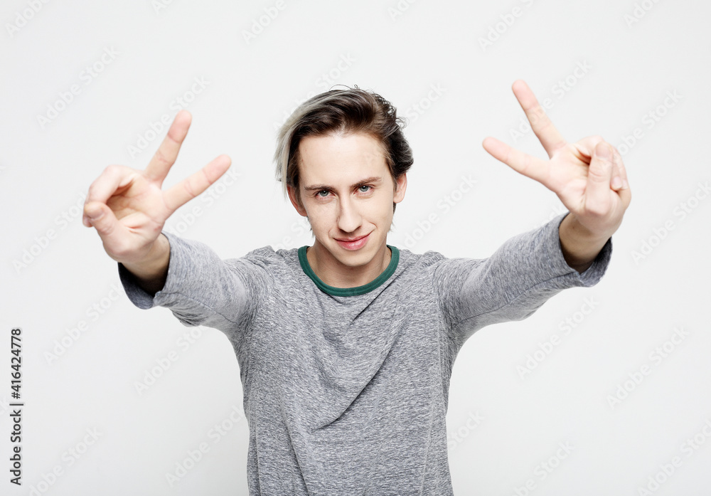happy young man making the victory or peace hand sign on white background happy young man making the victory or peace hand sign on white background