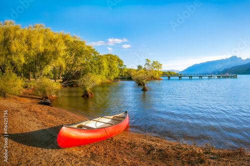 A red canoe on the shore of Lake Wakatipu at Glenorchy Wharf at golden hour in New Zealand, South Island Fototapet