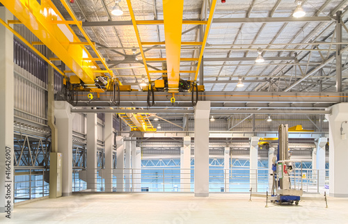 Concrete floor inside factory or warehouse building with empty space for industry background. Overhead crane or bridge crane include hoist lifting for transportation, manufacturing, and production.
