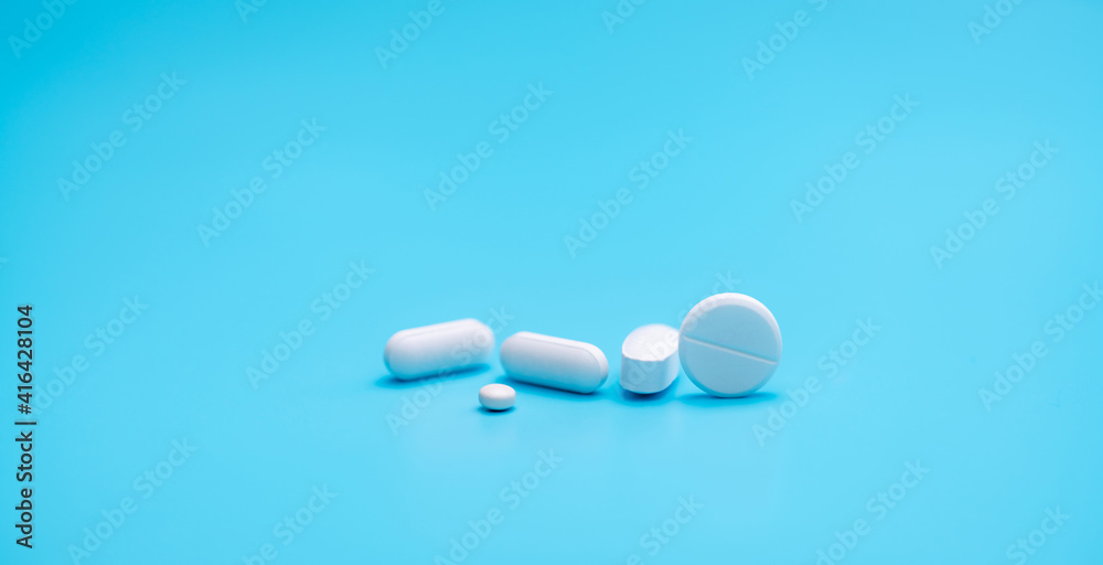 Round white tablets pills on blue background. Tablets and caplets pills