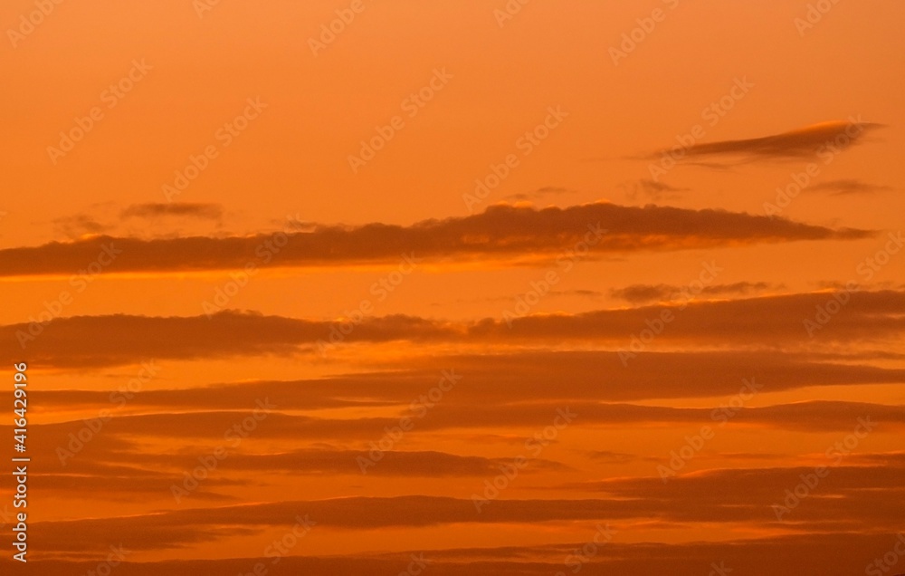 This image captures clouds floating through a warm sunset sky.