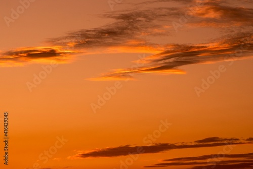 This image captures serene clouds in an orange sunset sky.