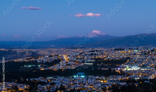 Aerial blue hour night cityscape of Quito with Cayambe volcano, Ecuador.