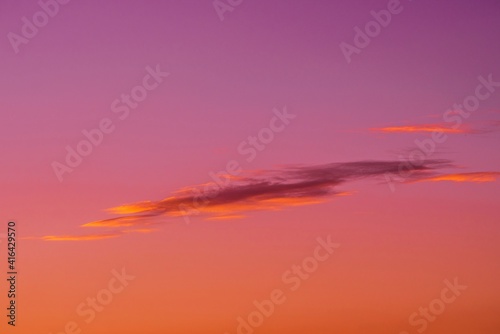 This image shows a lone cloud in a pink and purple sky, colored by an epic setting sun.