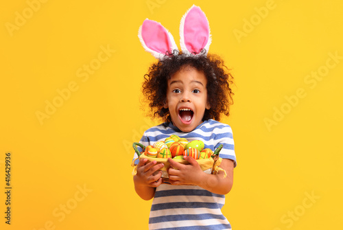 Excited sethnic kid holding Easter present in hands and laughing