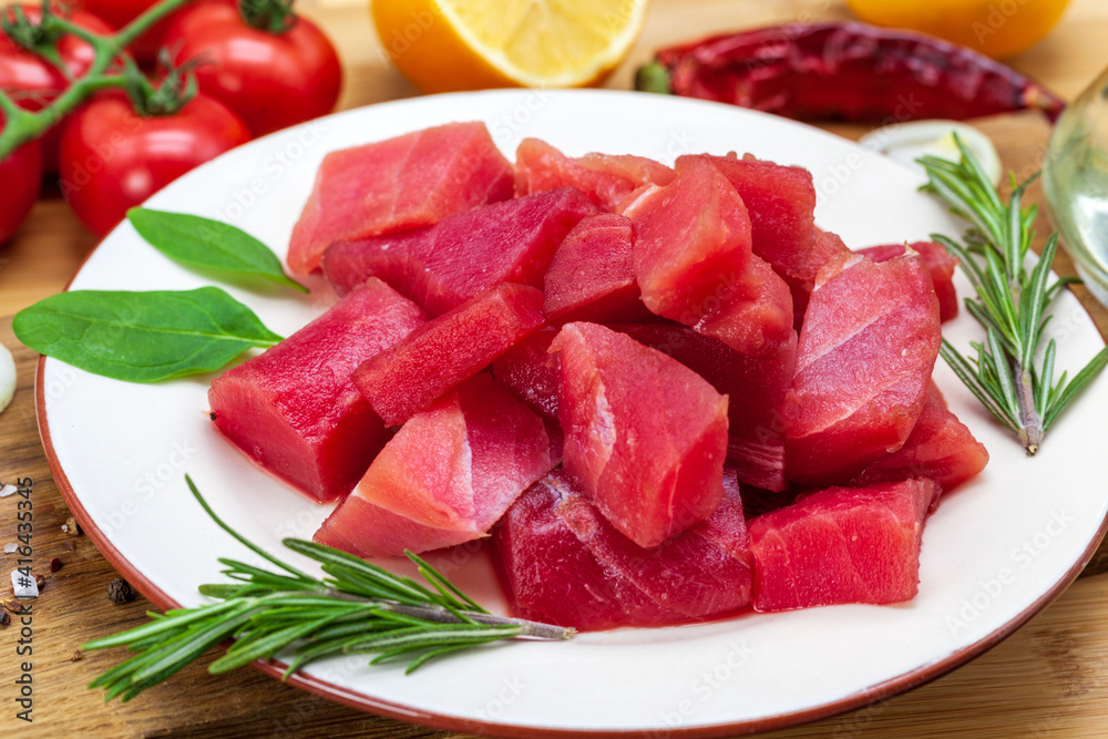 Fresh tuna fillet steaks with spices, vegetables and herbs on a plate. Preparing tuna for baking Fresh tuna fillet steaks with spices, vegetables and herbs on a plate. Preparing tuna for baking