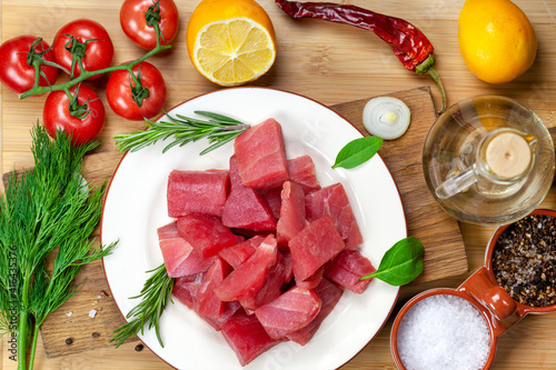 Fresh tuna fillet steaks with spices, vegetables and herbs on a plate. Preparing tuna for baking