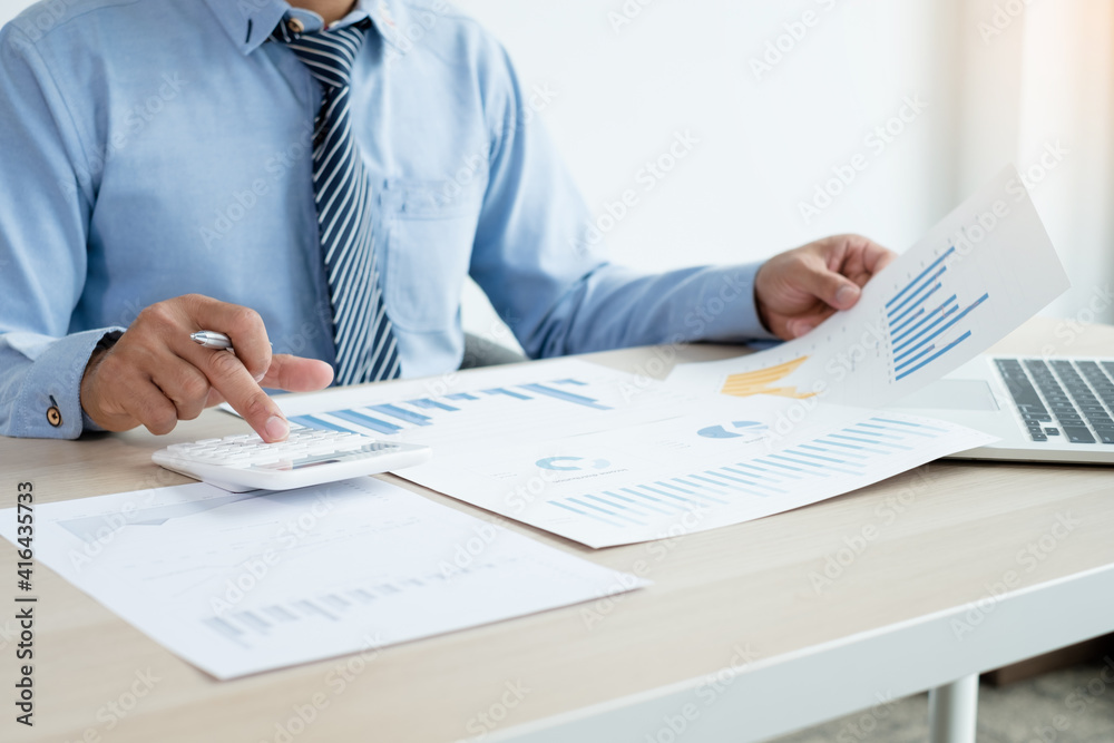The businessman's hand sits at their desks and calculates financial graphs showing results about their investments, plan a successful business growth process The businessman's hand sits at their desks and calculates financial graphs showing results about their investments, plan a successful business growth process