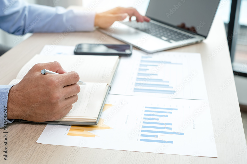 The businessman's hand sits at their desks and calculates financial graphs showing results about their investments, plan a successful business growth process The businessman's hand sits at their desks and calculates financial graphs showing results about their investments, plan a successful business growth process