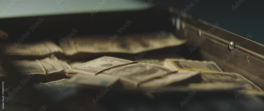 US Dollar banknotes falling into a suitcase full of money in slow motion. US Dollar banknotes falling into a suitcase full of money in slow motion.