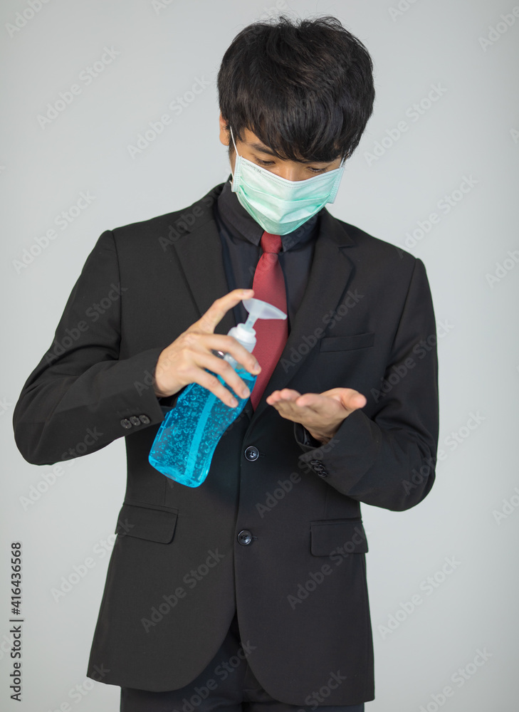 Businessman in suit and wearing protective hygiene mask holding alcohol gel and pouring on hand for demonstrating how to wash and sterilize hands for coronavirus protection Businessman in suit and wearing protective hygiene mask holding alcohol gel and pouring on hand for demonstrating how to wash and sterilize hands for coronavirus protection