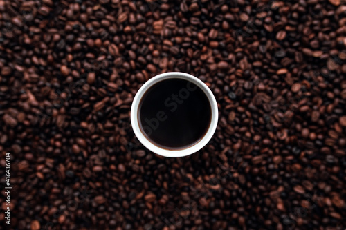 White cup of coffee on a bunch of roasted coffee beans background