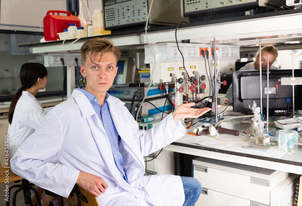 Male scientist sitting near laboratory equipment at biochemical lab