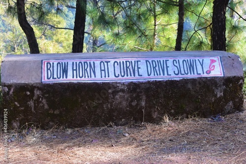 Blow horn at curve drive slowly sign outside the road in Himachal Pradesh India