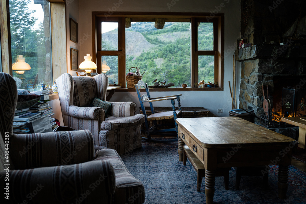 Cozy and beautiful large living room with sofas, little table and nature view windows in big wooden house