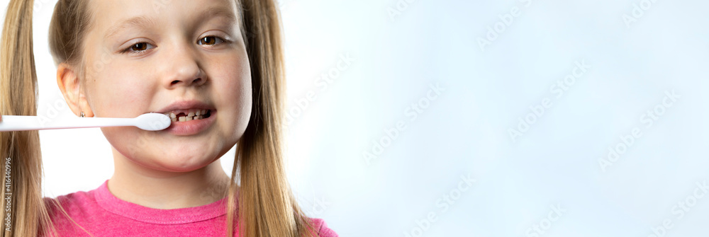 Preschool girl with a toothbrush. The milk tooth has fallen out, and a permanent tooth grows in the open mouth. Dental hygiene concept. Preschool girl with a toothbrush. The milk tooth has fallen out, and a permanent tooth grows in the open mouth. Dental hygiene concept.