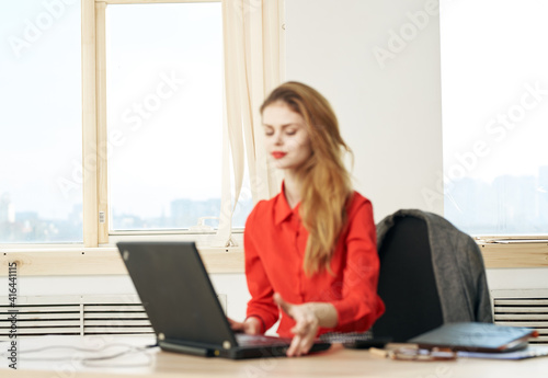 Woman secretary red shirt work desk laptop office manager