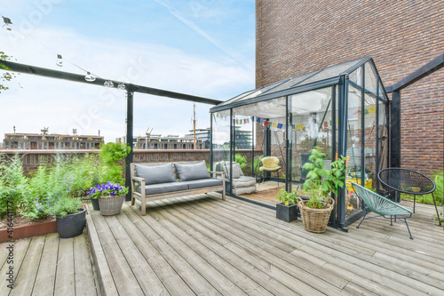 Fototapeta A large open-air terrace on the roof-top with lounge space and a small greenhous