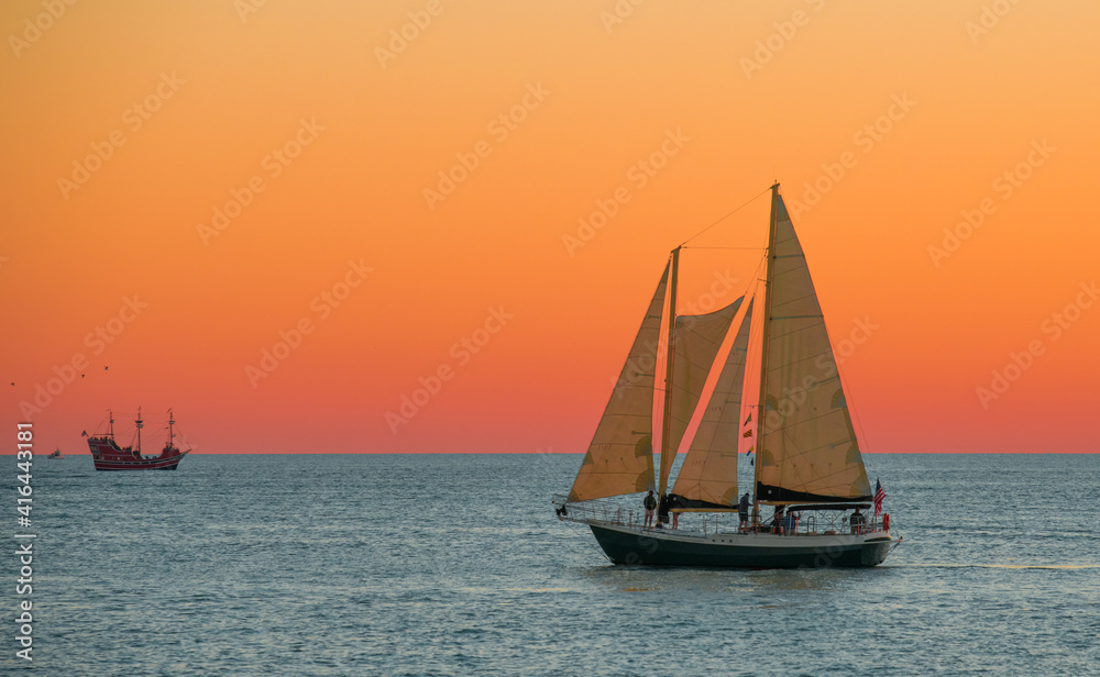 Sailboat or Sail yacht. Private cruise or sunset tour. Summer vacations on ocean or Gulf of Mexico Florida. Yachting sport. Beautiful seascape. Red sky after sunset. Sailboat or Sail yacht. Private cruise or sunset tour. Summer vacations on ocean or Gulf of Mexico Florida. Yachting sport. Beautiful seascape. Red sky after sunset.
