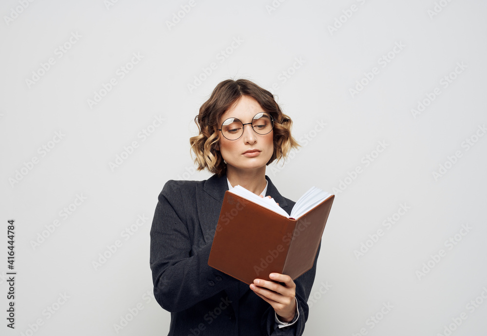 A woman in a suit with a notebook in her hands on a light background work model A woman in a suit with a notebook in her hands on a light background work model