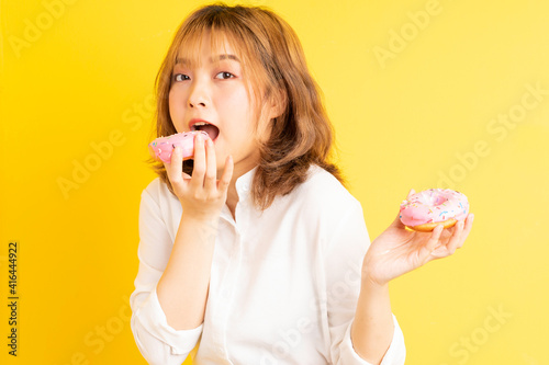 Young asian girl holding donut with cheerful expression on background